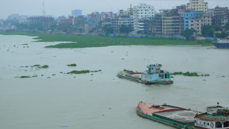 river scene with barges and cityscape in bangladesh