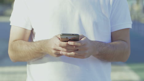 cropped shot of man wearing white t-shirt using smartphone.