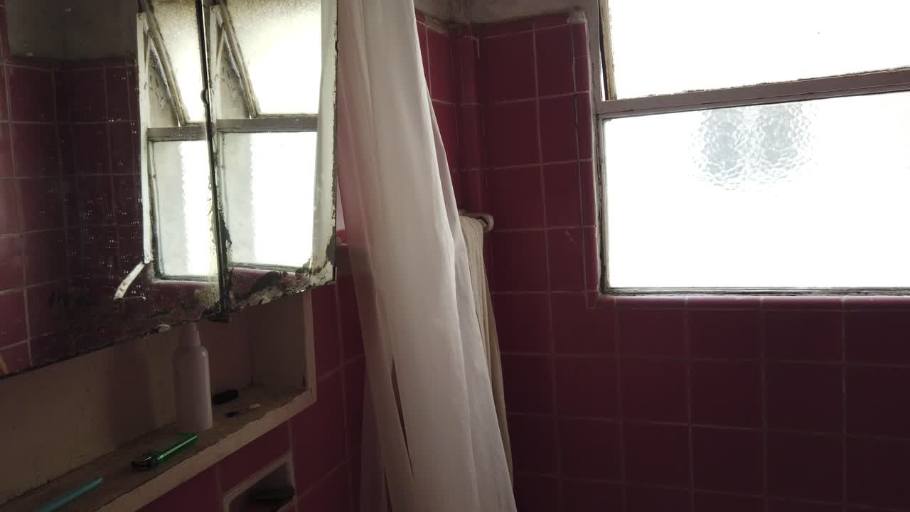 Handheld of Old Vintage Bathroom with Pink Tiles and Weathered Mirror Cabinet