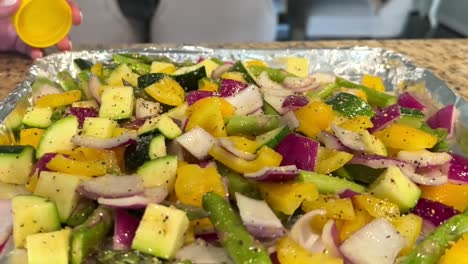 sprinkling seasoning over cut vegetables on tray ready to be cooked