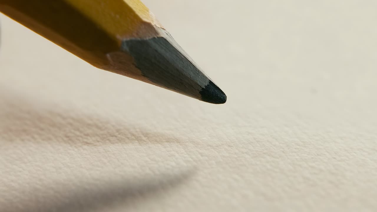 Eine gelbe Bleistiftspitze senkt sich auf raues Papier, ein Finger stabilisiert den langen Schatten, der schrumpft und einen Punkt hinterlässt