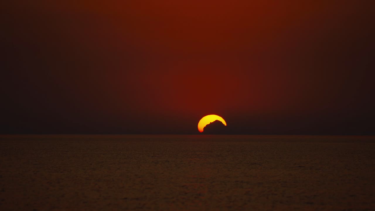 크로아티아 지중해 해변의 낭만적인 해변에서 여름에 커다란 주황색 공처럼 수평선 너머로 지는 태양의 시간 경과