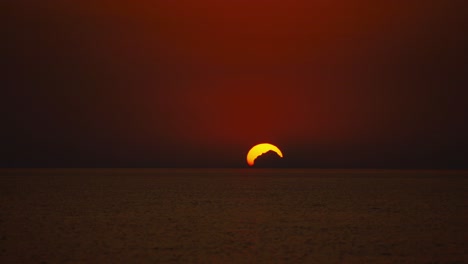 lapso de tiempo de la puesta de sol sobre el horizonte en una playa romántica en la costa mediterránea croata como una gran bola naranja en verano