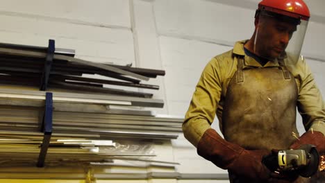 welder cutting metal with electric tool in workshop