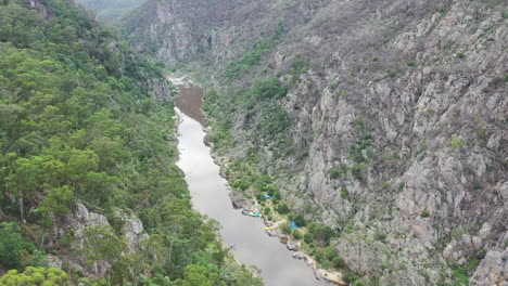 la antena desciende por las paredes rocosas del cañón arbolado hasta el campamento en un río tranquilo