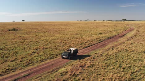 Luftdrohnenaufnahme-Eines-Naturfotografen,-Der-Ein-Safarifahrzeug-In-Der-Savanne-Des-Maasai-Mara-National-Reserve,-Kenia,-Afrika,-Mit-Wunderschöner-Landschaftskulisse,-Masai-Mara-North-Conservancy,-Fährt