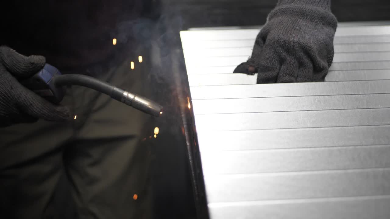 금속 용접공은 보호 장비를 갖춘 공장에서 강철 용접공과 함께 일합니다