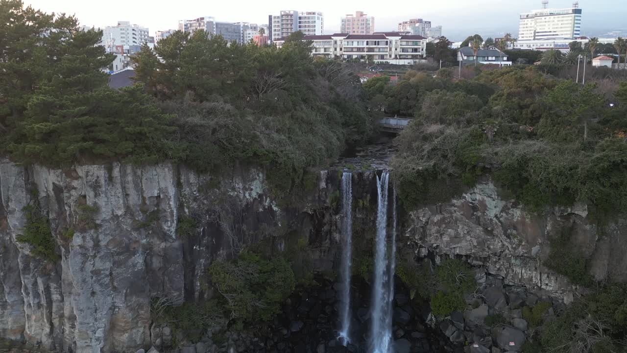 Drone aerial view in South Korea flying in front of a waterfall over the sea rocky area jeju island
