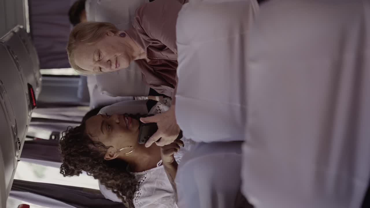 Two women interact with a phone on a bus