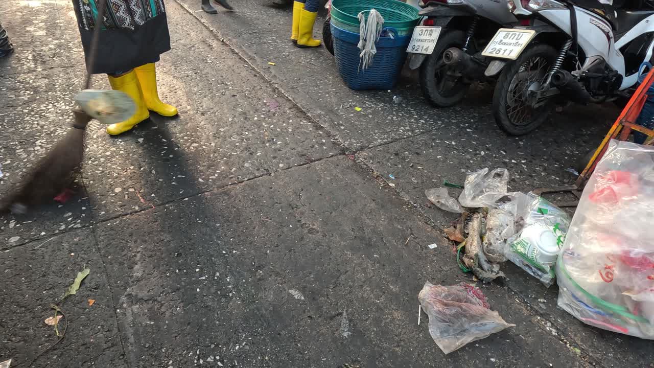 persona barriendo la basura de una calle concurrida