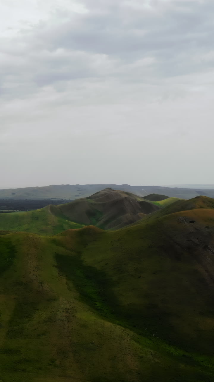Perbukitan Hijau Bergulir yang Berawan Dengan Lembah Dalam, Survei Drone Geolog Menangkap Tekstur yang Suram dan Berbayang.