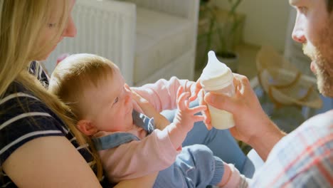 Mid-adult-caucasian-parents-feeding-milk-her-baby-from-bottle-in-a-comfortable-home-4k