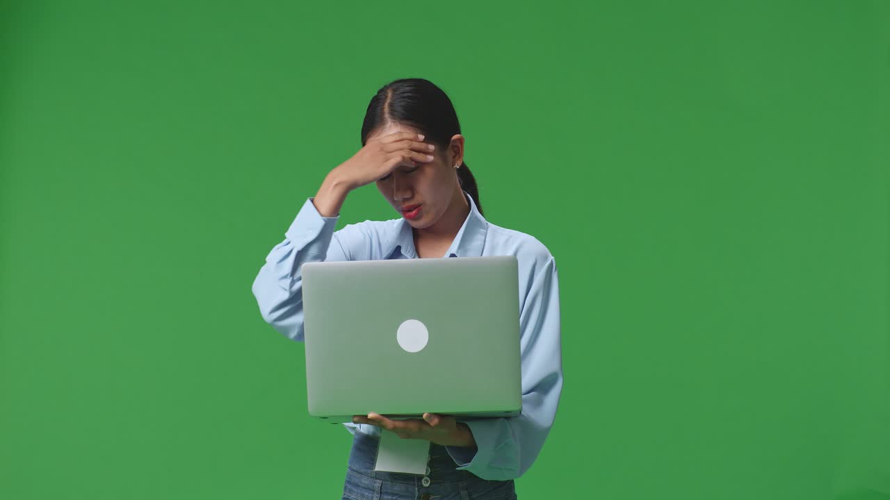 una mujer de negocios asiática no está satisfecha y sacude la cabeza mientras usa una computadora portátil en un estudio de pantalla verde