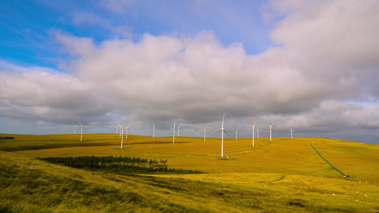 Timelapse of Wind Farm Over Open Moorland with Dark Cloud Shadows Moving Over Landscape as Turbines Spin Rapidly Generating Clean Renewable Electricity