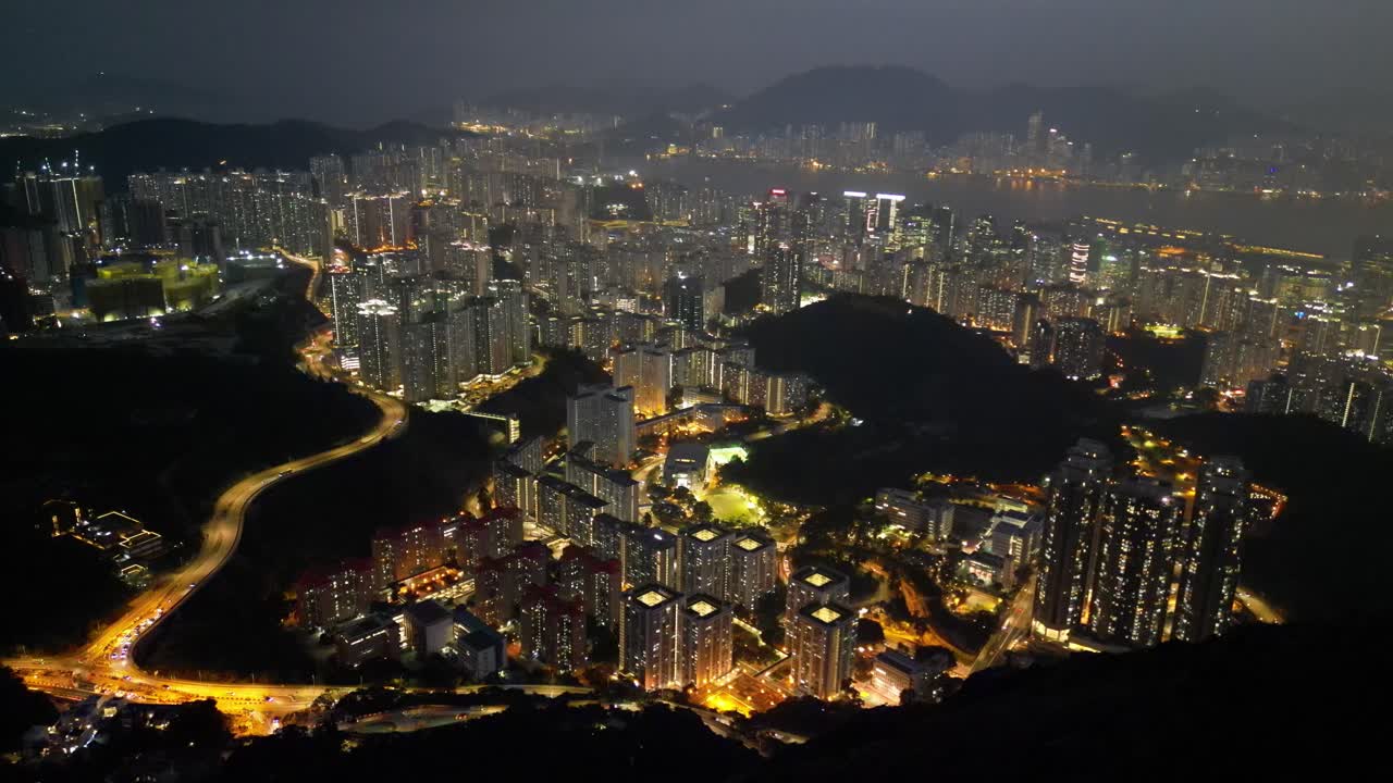 Aerial drone footage of Hong Kong city at night featuring illuminated skyscrapers, glowing skyline, and vibrant reflections showcasing the city’s modern architecture and lively urban beauty