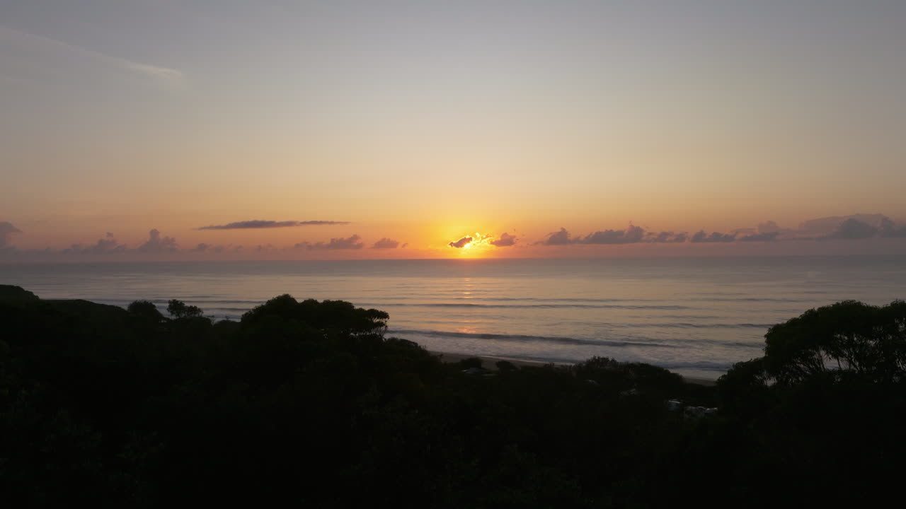 Ascending drone shot showing majestic sunset reveal of ocean at Gillards' beach, NSW, Australia