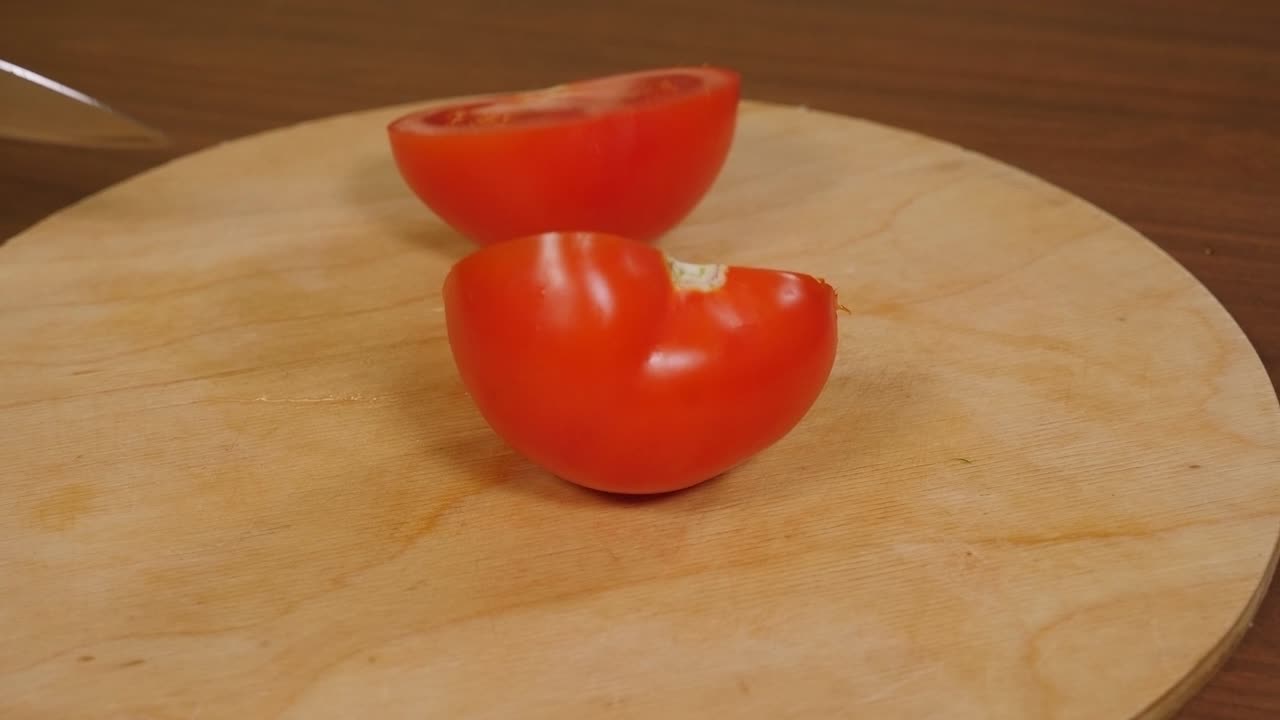 나무 기 보드에서 토마토를 반으로 잘라내는 여자의 클로즈업입니다.