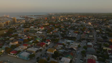 Toma-Aérea-De-Diapositivas-Y-Panorámicas-De-Edificios-En-Un-Barrio-Urbano-Residencial-Al-Atardecer.-Puerto-Elisabeth,-Sudáfrica