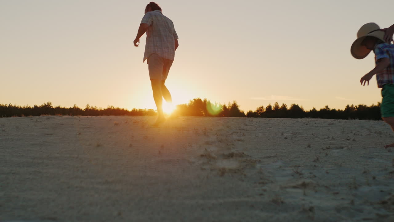 Young Happy Father Playing With His Two Sons Run Away And Laughing At Sunset