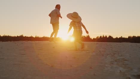 young happy father playing with his two sons run away and laughing at sunset