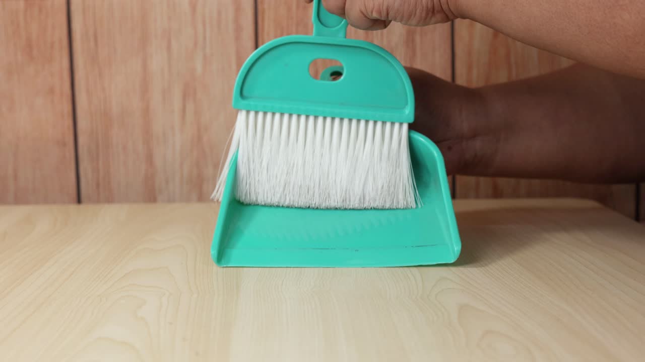 el uso de una sartén y un pincel para limpiar la superficie