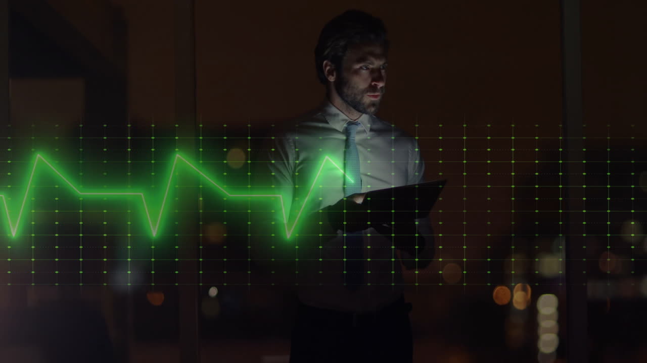 Male office worker holding tablet in night high-rise office, displaying health ECG waveform grid