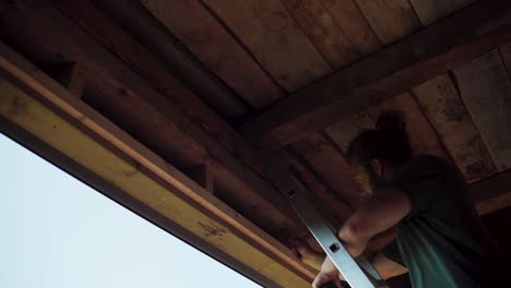 caucasian carpenter on a ladder inside wooden cottage