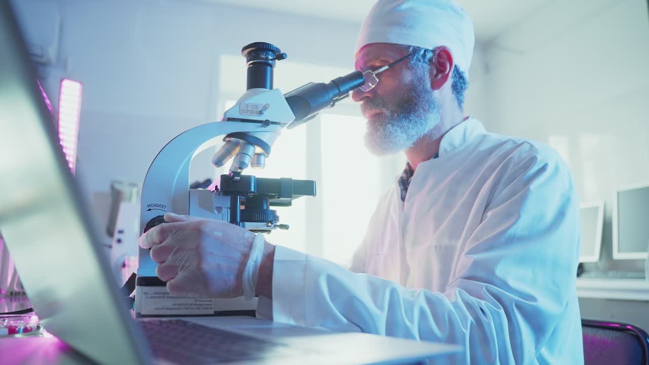 Male Scientist Working with Microscope and Laptop in a Modern Laboratory