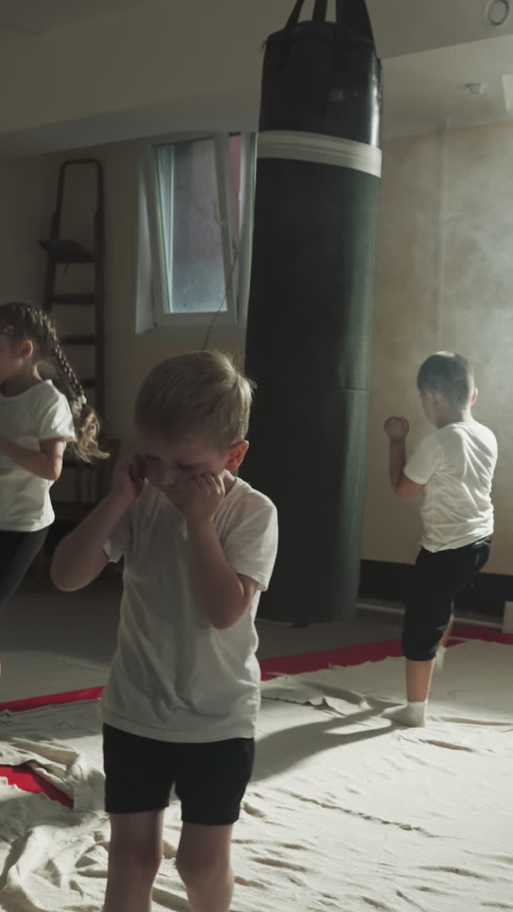 los niños y los deportistas adultos entrenan juntos en el club de kickboxing. los luchadores hábiles y pequeños se ejercitan con equipos de golpeo en el gimnasio de artes marciales. deportes para diferentes generaciones