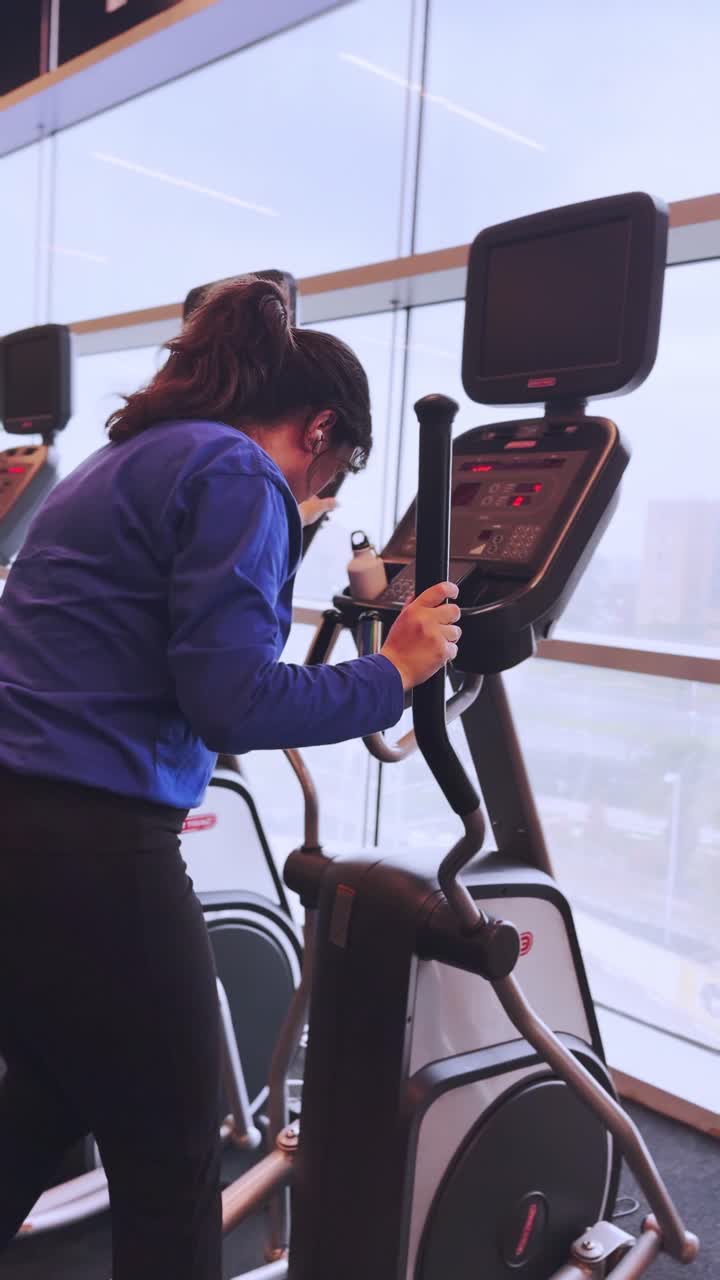 Young woman working out on elliptical trainer in gym