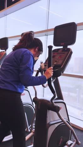 young woman working out on elliptical trainer in gym