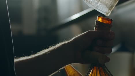 chef pouring sauce from glass jar into pitcher