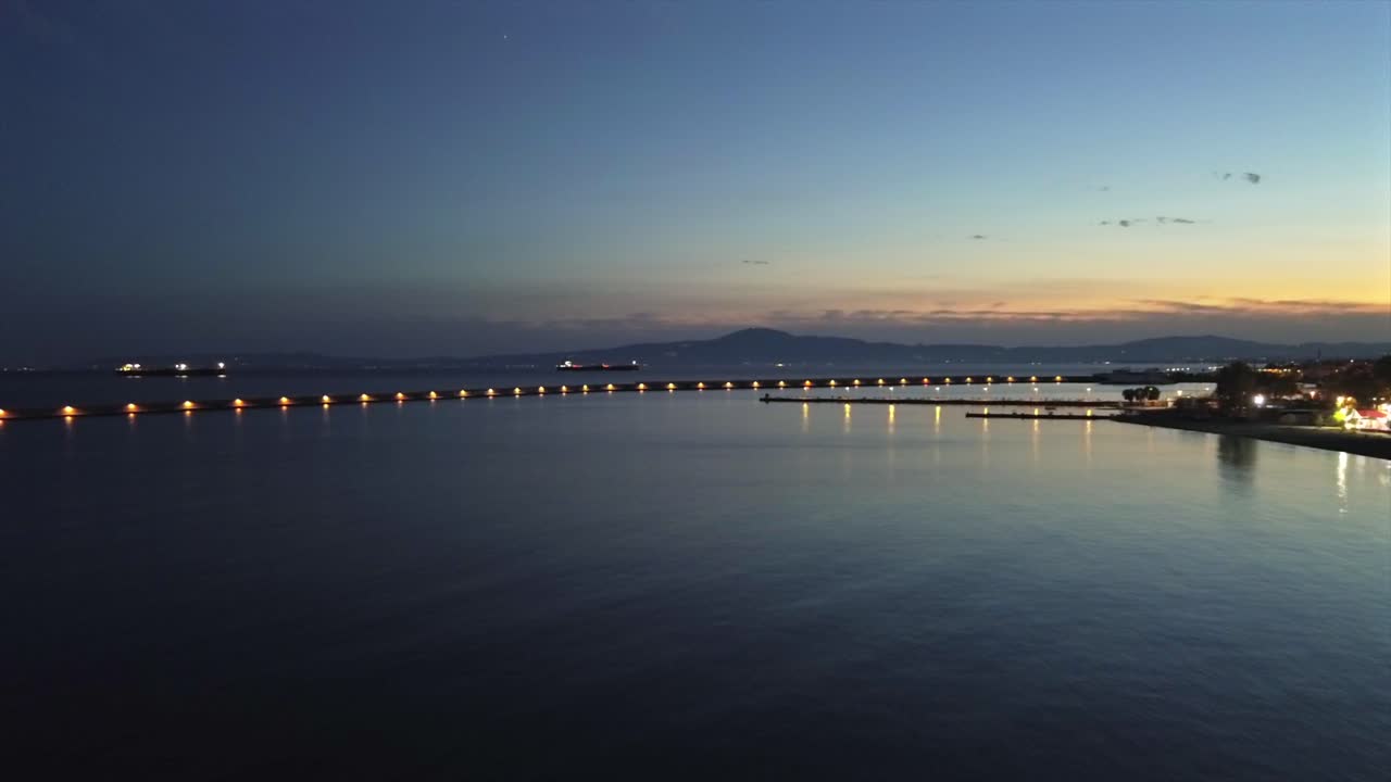 Aerial push in footage, flying towards iconic one kilometer Pier at port of Kalamata, Peloponnesus, Greece. Golden hour , dusk, beautiful sunset 4K