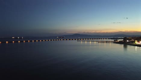 aerial push in footage, flying towards iconic one kilometer pier at port of kalamata, peloponnesus, greece. golden hour , dusk, beautiful sunset 4k