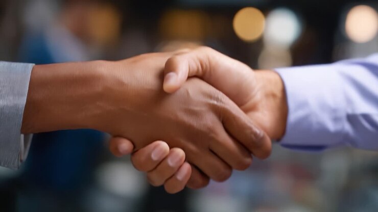 Due persone che si stringono la mano saldamente, a simboleggiare accordo, cooperazione o partnership in un ambiente professionale o aziendale con sfondo sfocato