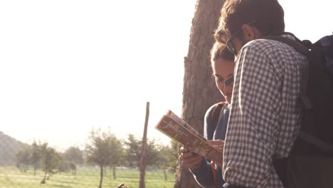 happy young couple backpackers tourists reading map guide for directions lost near roman aqueduct arches in parco degli acquedotti park ruins in rome at sunrise with guitar and sleeping bag slow motion steadycam