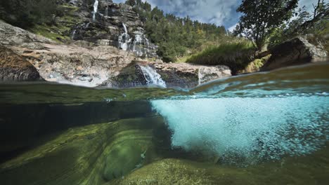 la impresionante vista de las orillas rocosas de un río poco profundo y el agua clara, y una cascada escénica