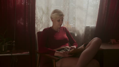 mujer leyendo un libro junto a la ventana