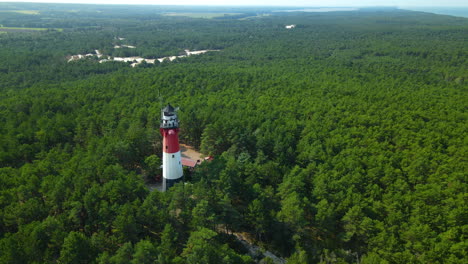 stunning view of lighthouse stilo surrounded by a dense foliage forest landscape in sasino, poland during daytime