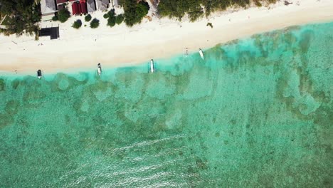 Beautiful-sea-texture-with-abstract-pattern-of-coral-reefs-and-pebbles-under-turquoise-water-of-lagoon-washing-white-sandy-beach-in-Turks-and-Caicos