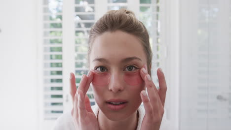 Biracial-woman-applying-under-eye-patches-in-bathroom,-slow-motion