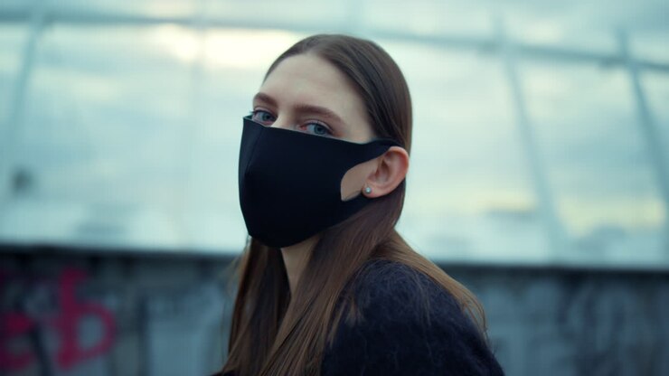 Woman wearing protective mask during protest. Girl in mask looking at camera