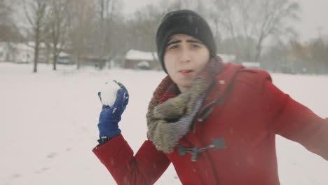 mujer con ropa roja de invierno lanzando bolas de nieve hacia la cámara en un frío día de invierno - mano, plano medio