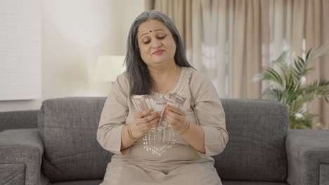 una anciana india feliz contando dinero.