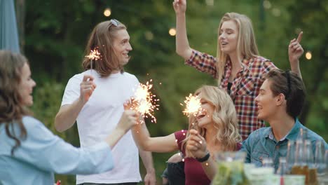 happy friends with sparklers having fun outdoors