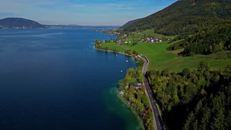 Vista-Aérea-Siguiendo-Una-Carretera-En-La-Costa-Del-Lago-Attersee,-La-Soleada-Austria