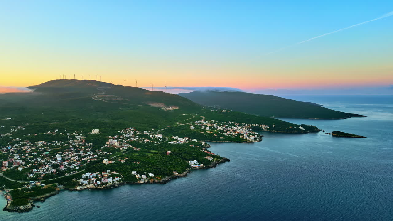 Aerial, drone view of buildings on the shore of the Adriatic sea, with mountains on the background in Montenegro