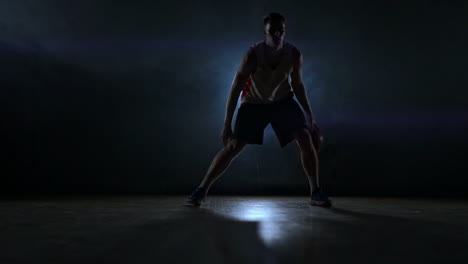 Skill-dribbling-basketball-player-in-the-dark-on-the-basketball-court-with-backlit-back-in-the-smoke.-Slow-motion-streetball