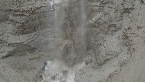 Aerial-tilt-shot-of-a-powerful-Big-flood-muddy-waterfall-in-the-Israeli-Judean-desert,-drone-shot