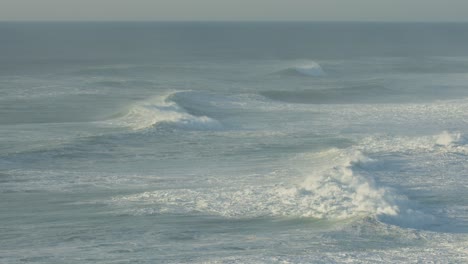 sets of waves roll along the coastline at nazaré north beach